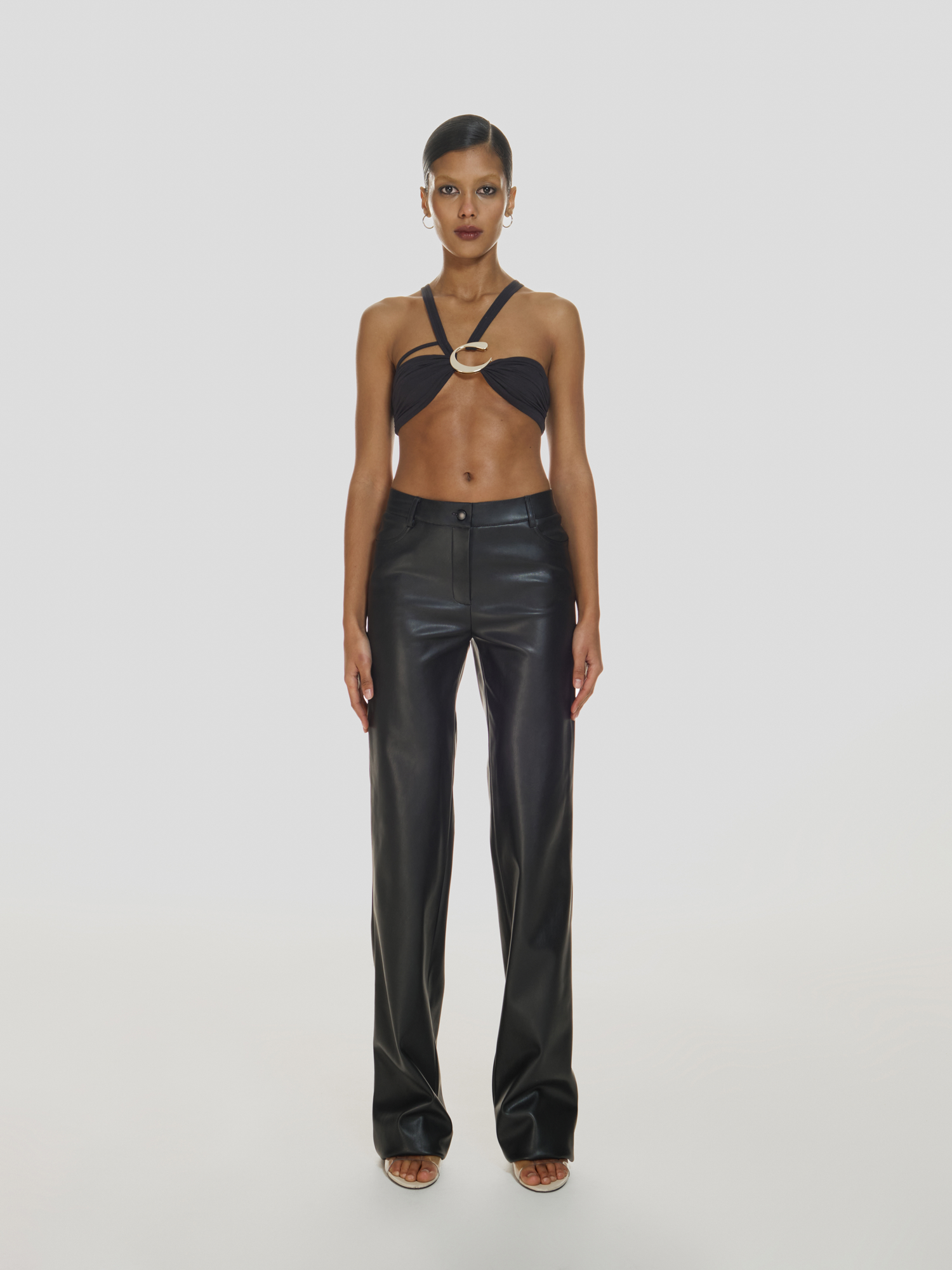 Full shot of a girl in a black crop top and black genuine leather pants with mid rise