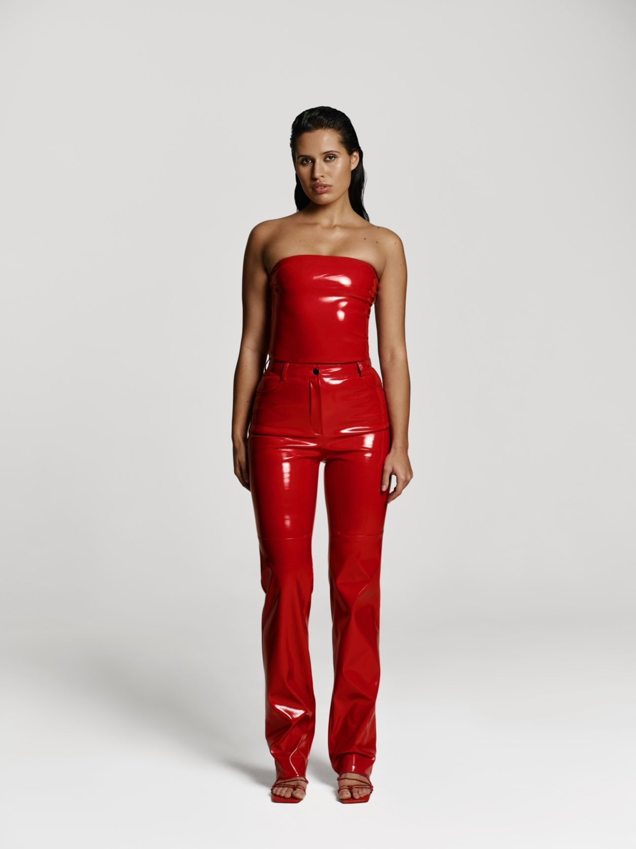 Full shot of a girl in a red patent vegan leather tube top and red patent vegan leather pants with straight leg