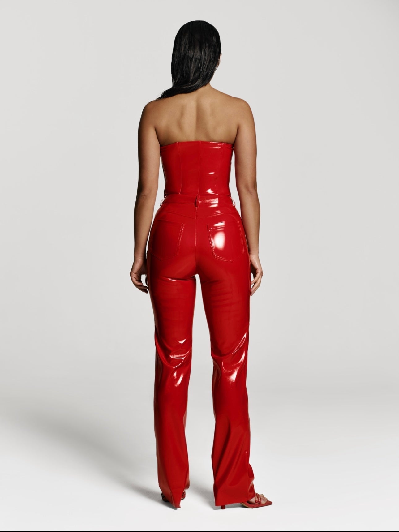 Full shot of a girl facing back in a red patent vegan leather tube top and red patent vegan leather pants with straight leg