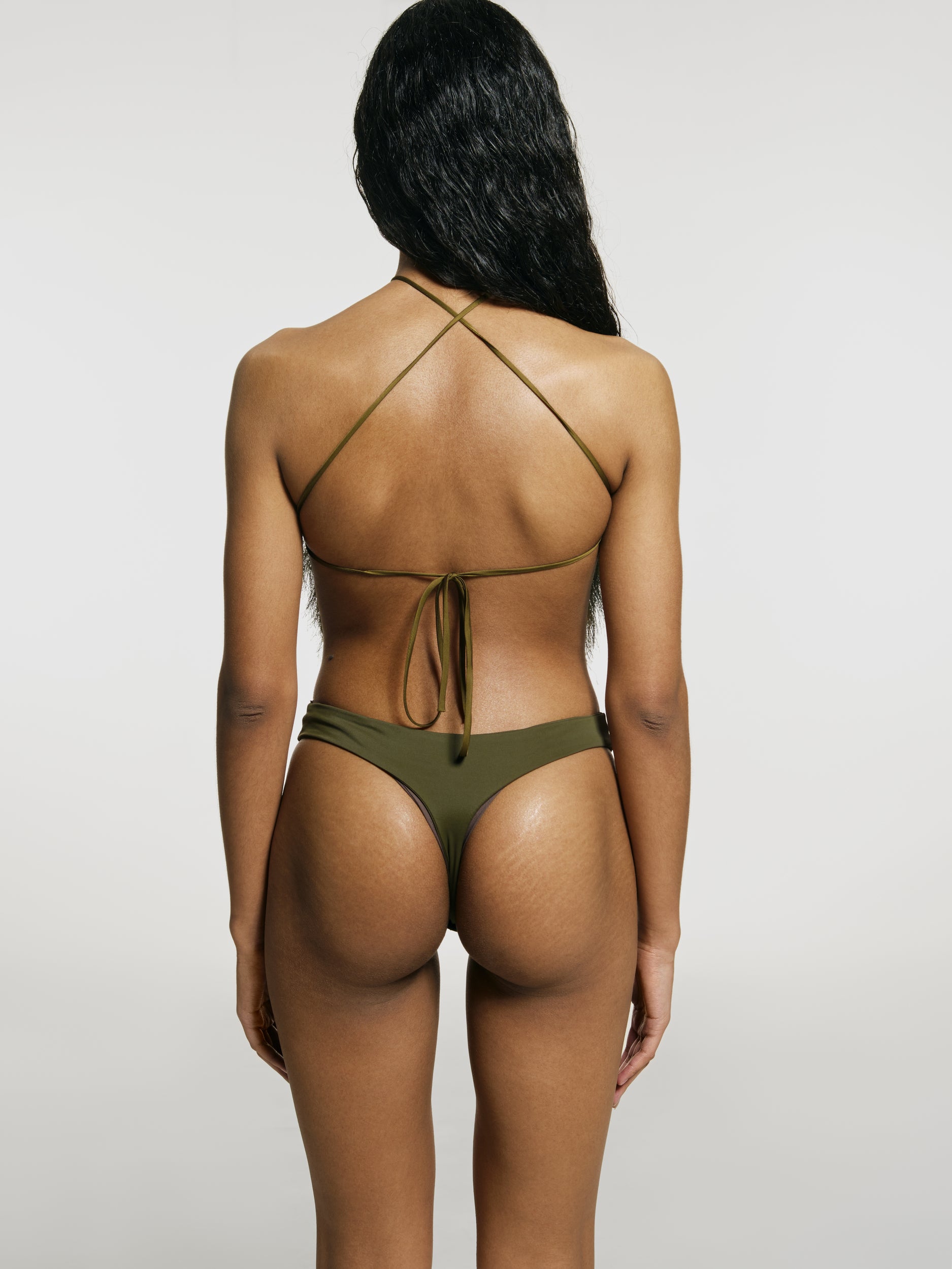 Medium full shot of a girl facing back in a green opened back sleeveless bodysuit with a vertical cut in front