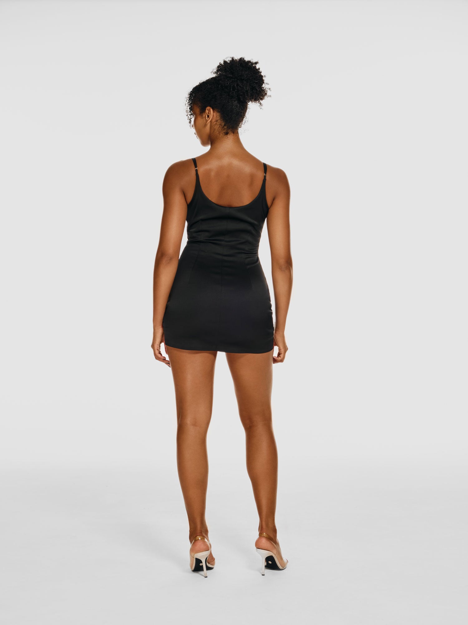 Full shot of a girl facing back in a black mini dress, featuring shorts underneath