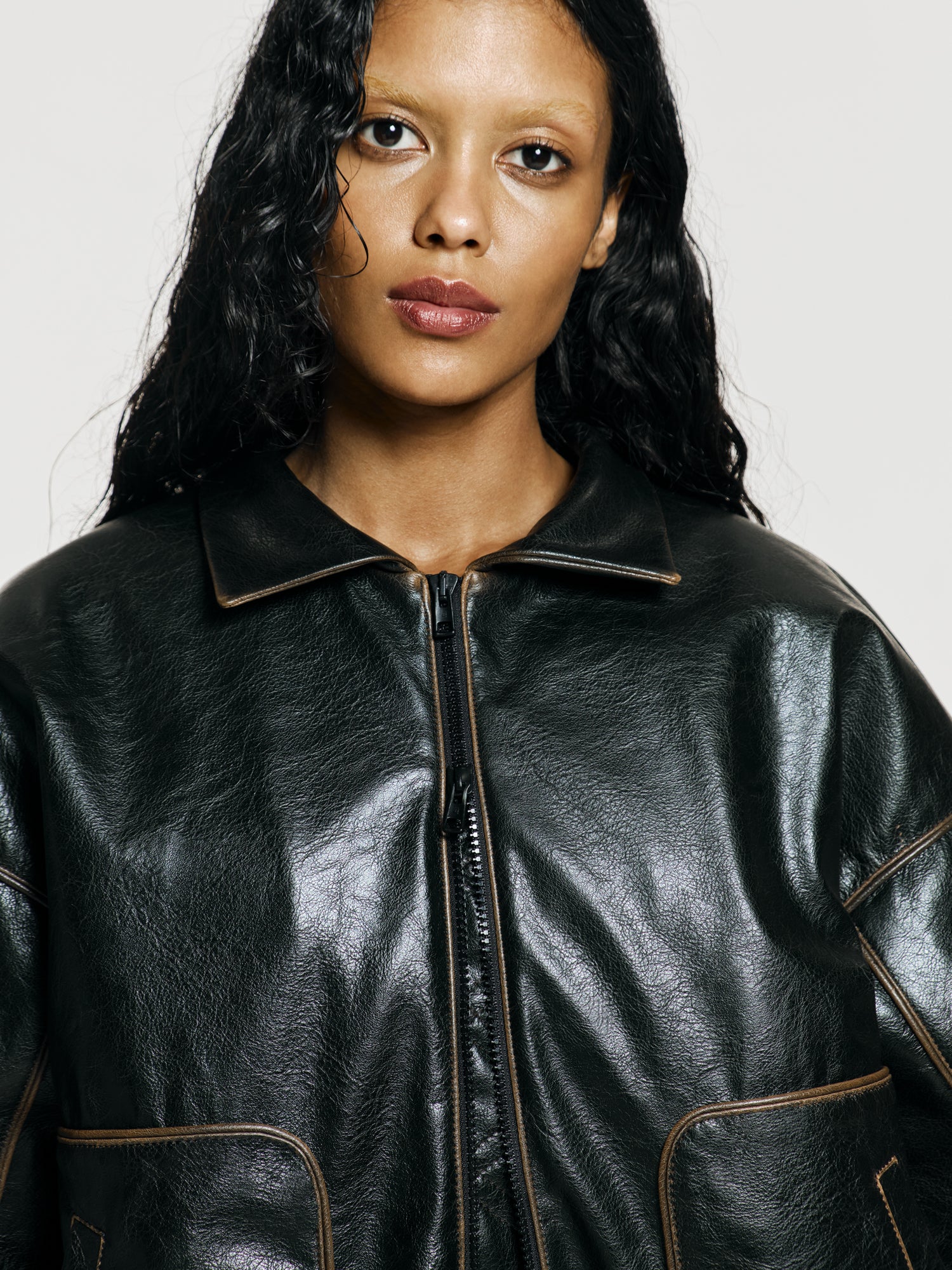 Medium closeup shot of a girl in a brown vegan leather oversized bomber