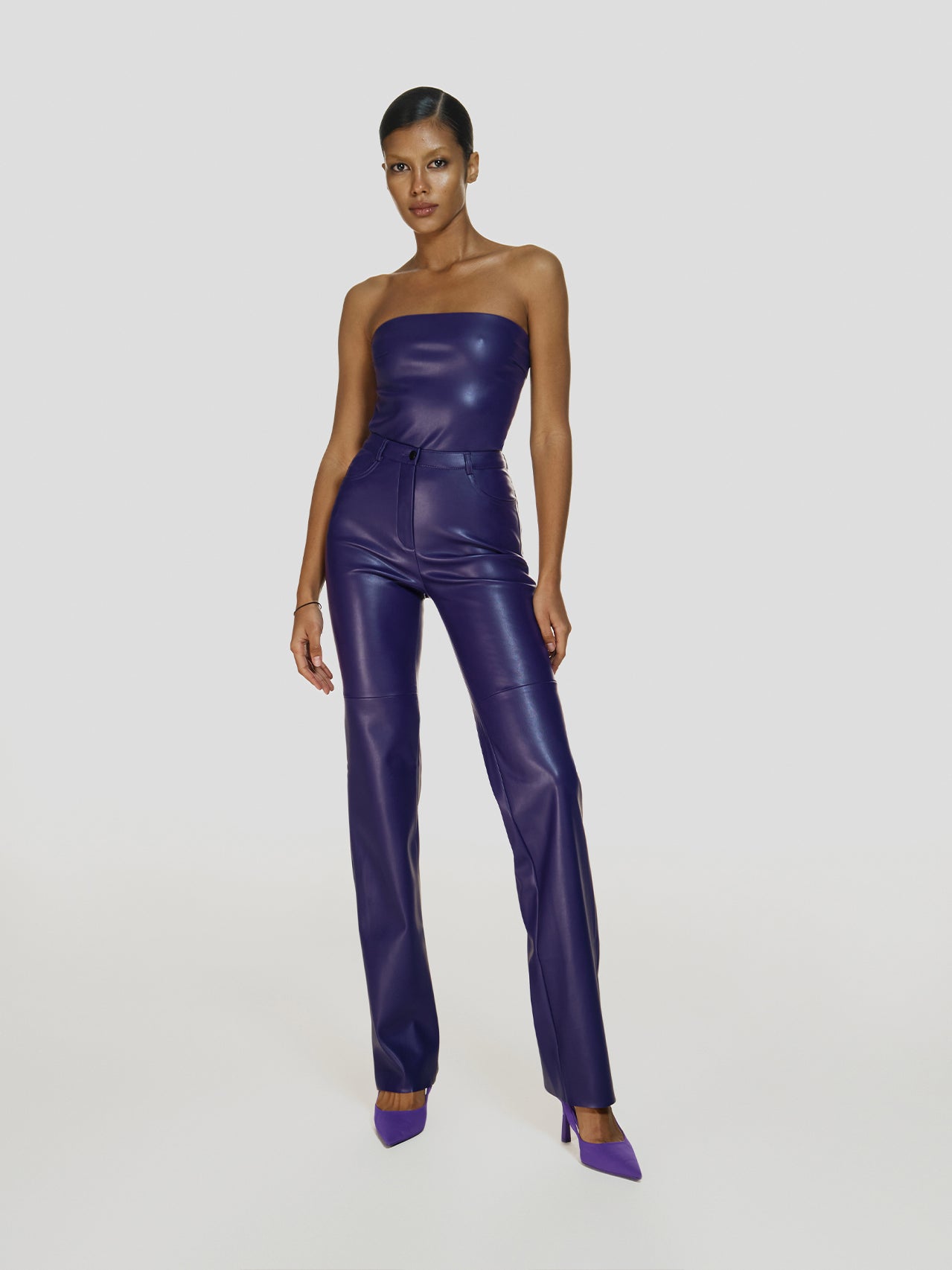 Full shot of a girl in a purple vegan leather tube top and purple vegan leather high rise pants with straight leg