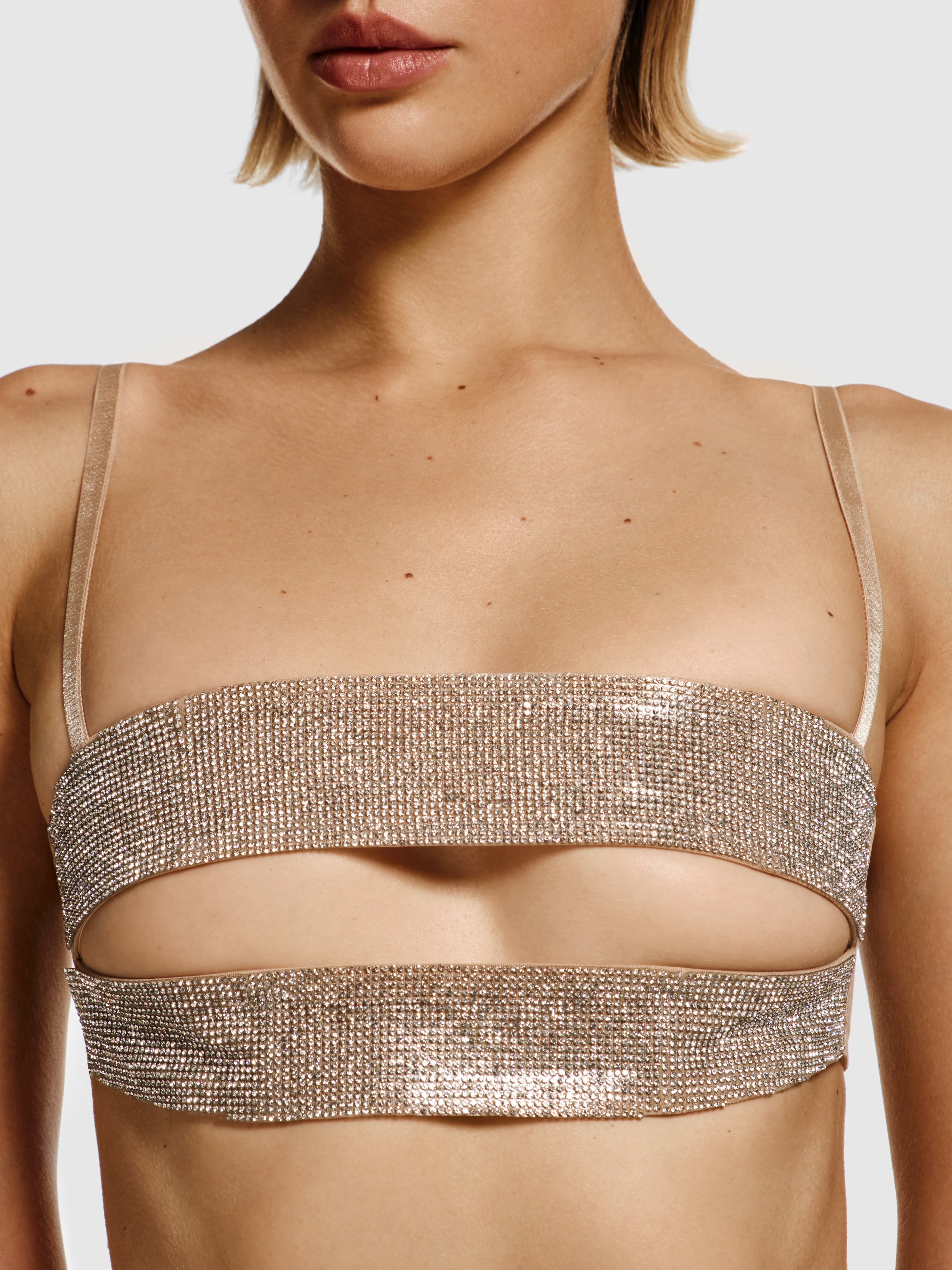 Medium closeup shot of a girl in nude beige a crop top decorated with rhinestones, featuring horizontal cut