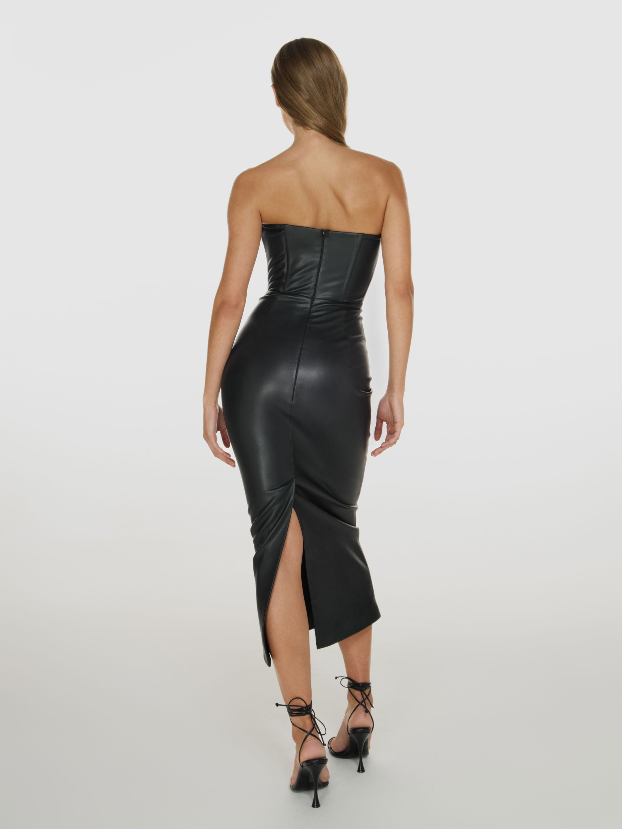 Full shot of a girl facing back in a black vegan leather tube dress