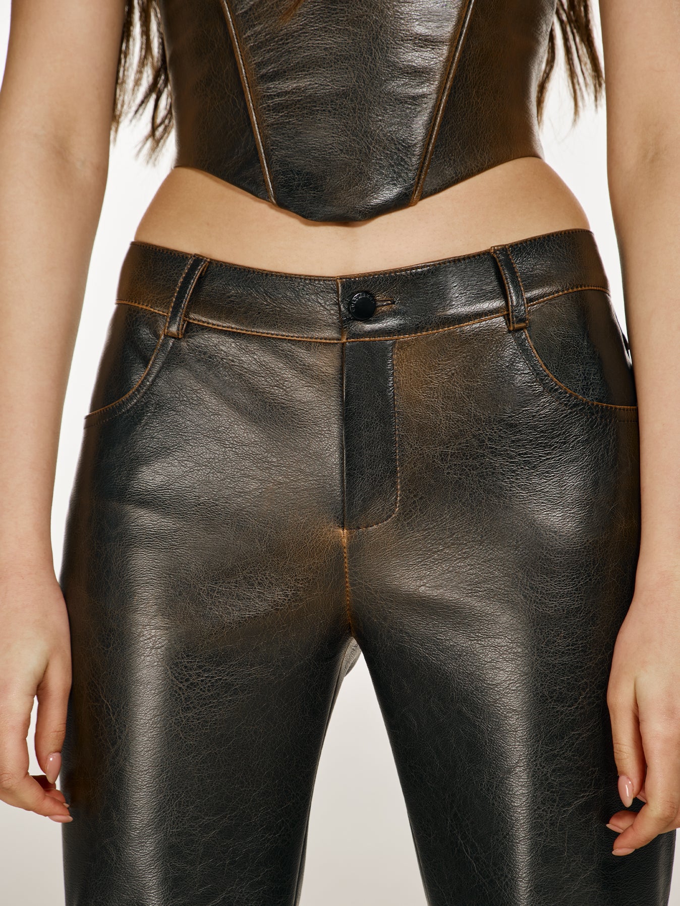 Closeup shot of a girl in a brown vegan leather tube top with V neck and brown vegan leather pants with mid rise
