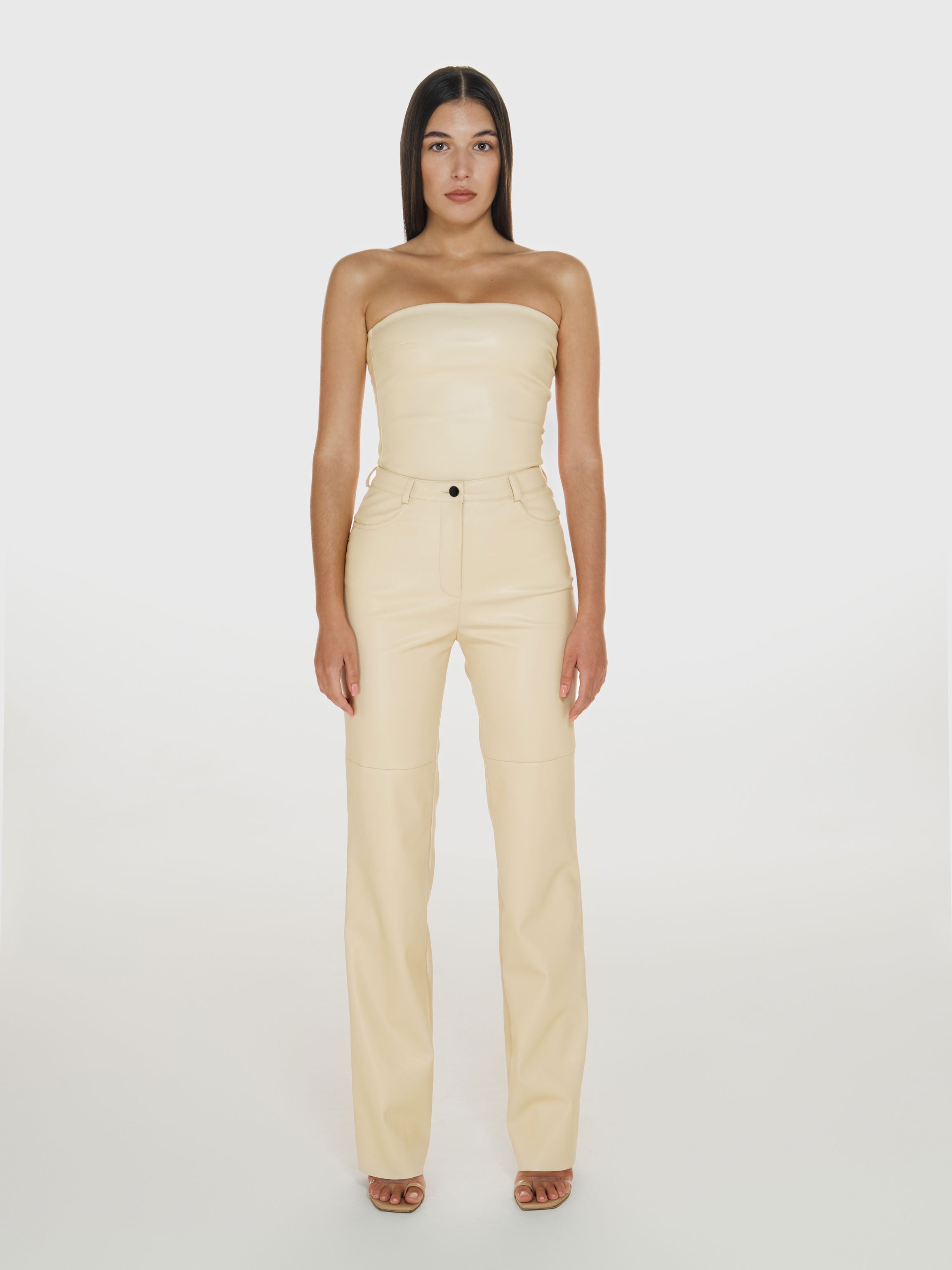 Full shot of a girl in a cream vegan leather tube top and cream vegan leather high rise straight leg pants