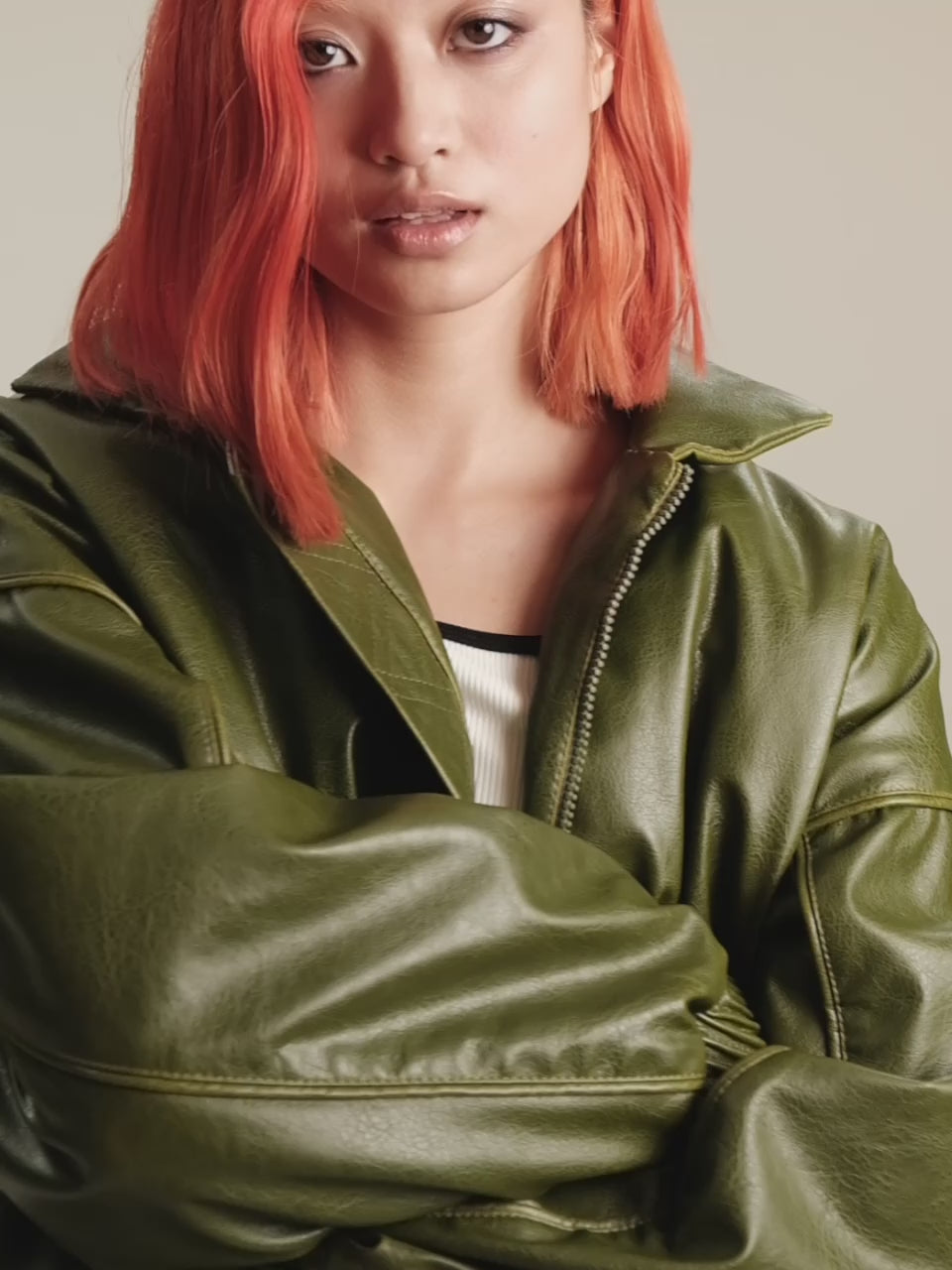 Video of medium and medium closeup shots of a girl in a green vegan leather oversized bomber, a white viscose crop top and black viscose high rise briefs
