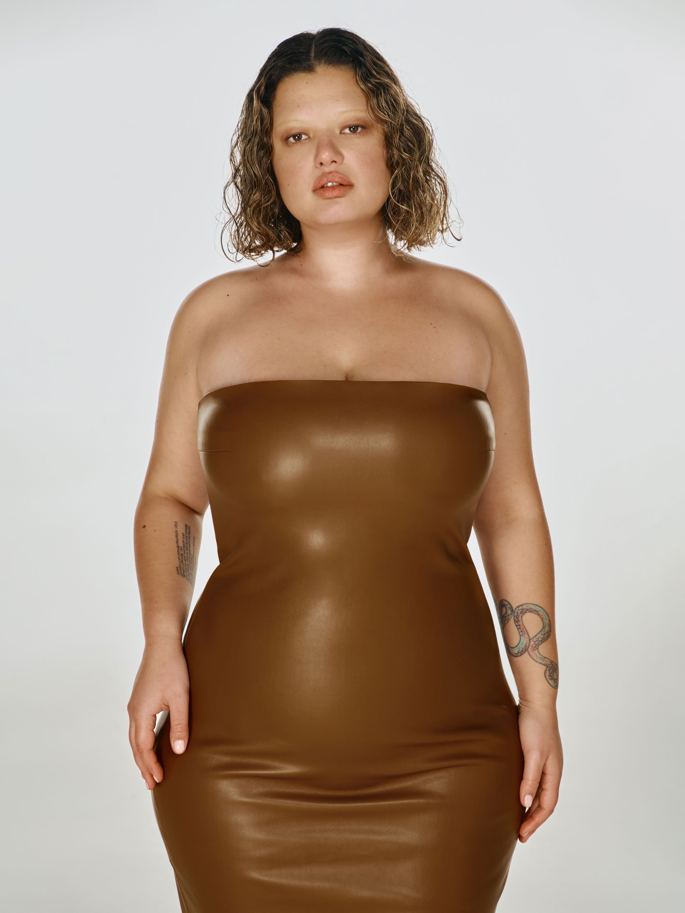 Cowboy shot of a girl in a brown vegan leather tube dress