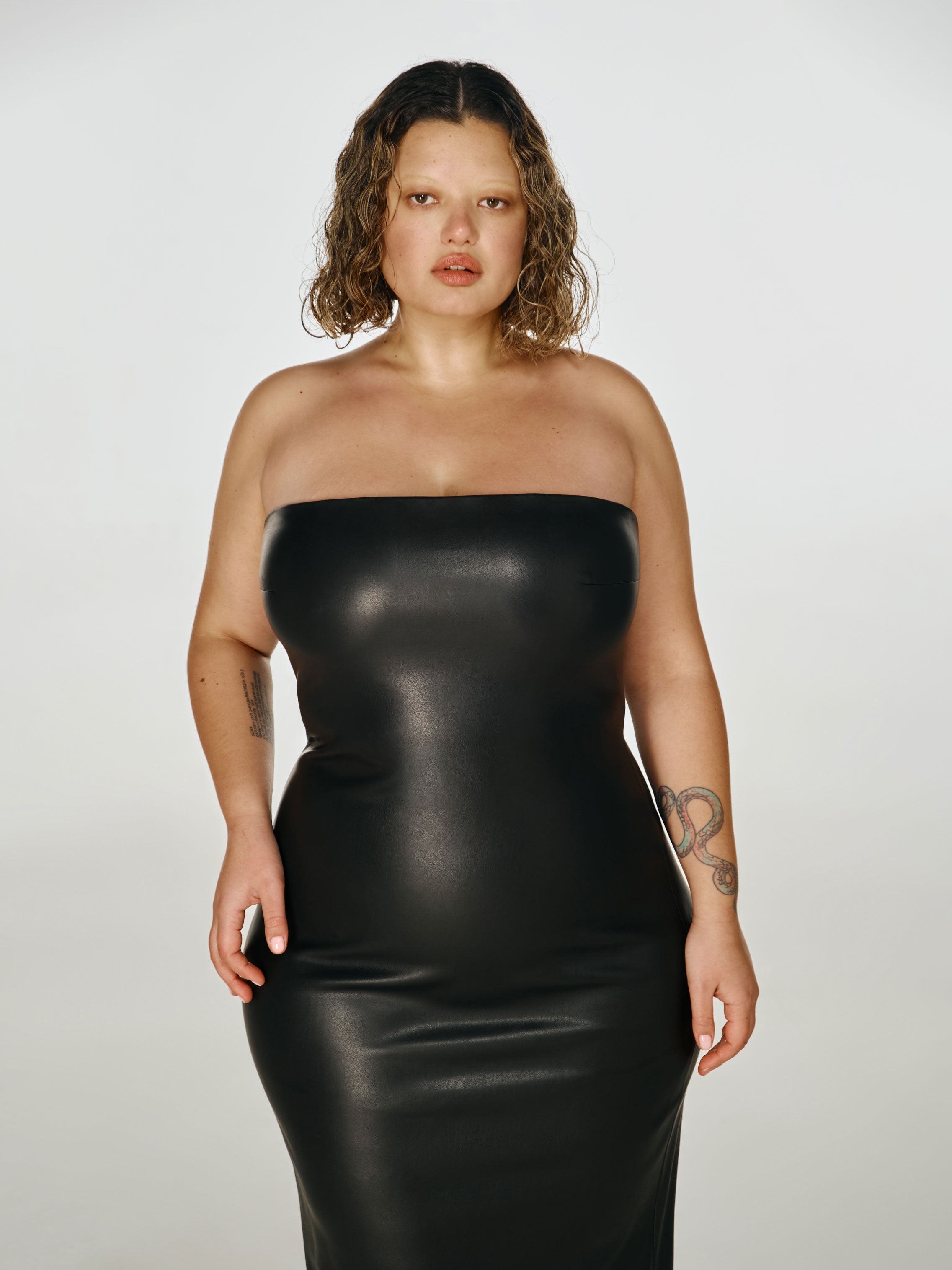 Medium full shot of a girl in a black vegan leather tube dress