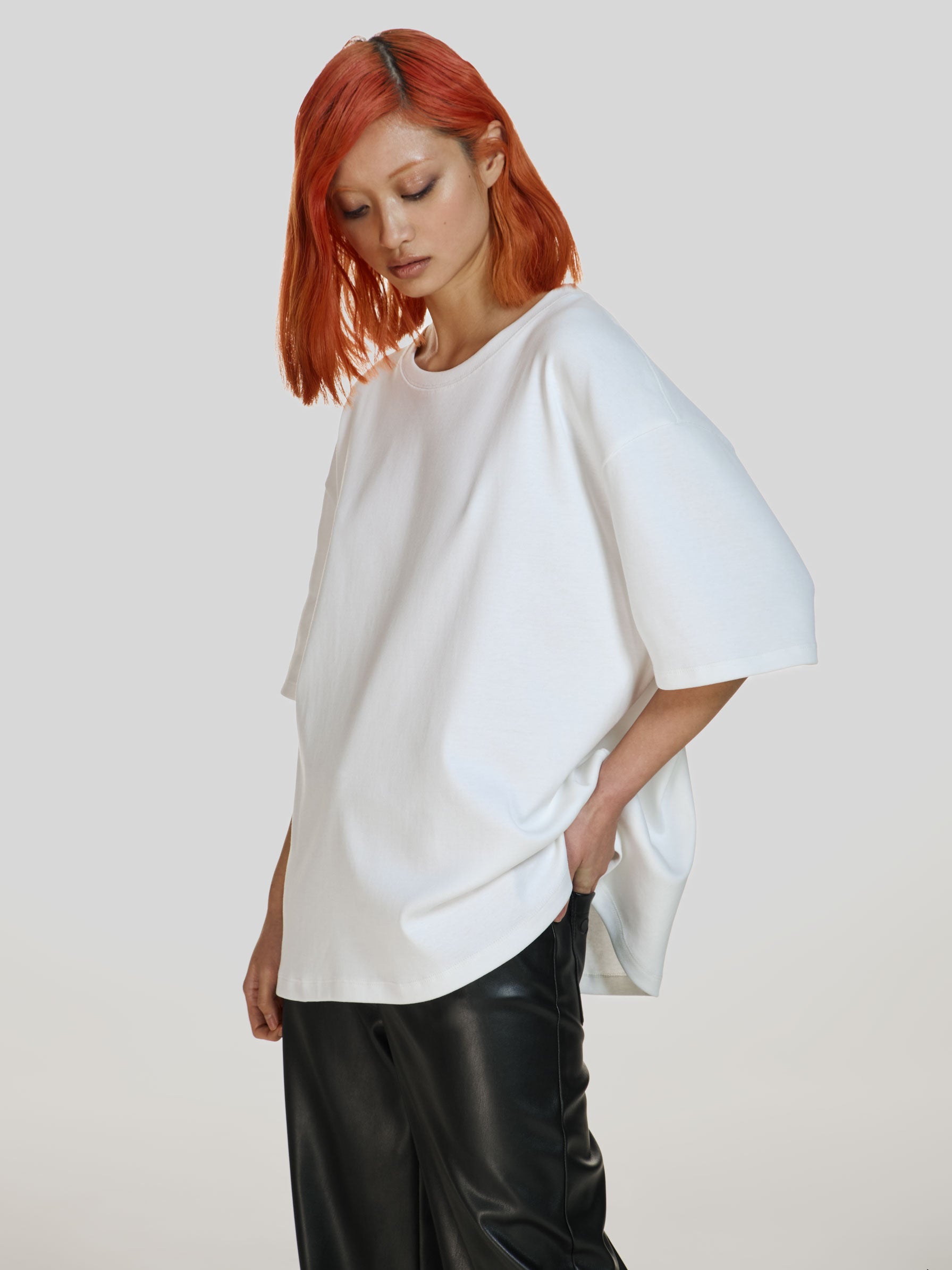 Medium full shot of a girl in a white cotton oversized t-shirt and black vegan leather straight leg pants