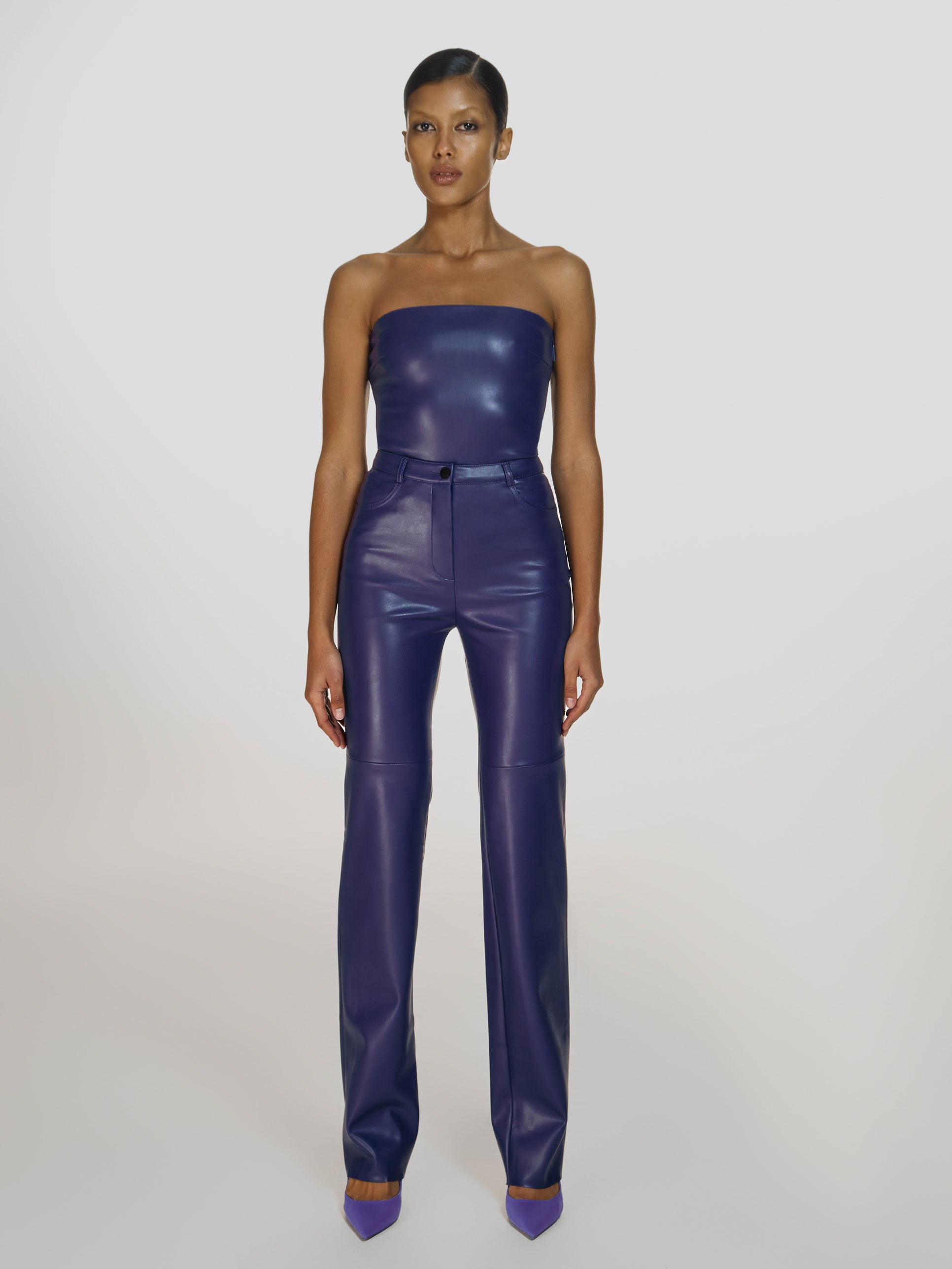 Full shot of a girl in a purple vegan leather tube top and purple vegan leather high rise straight leg pants