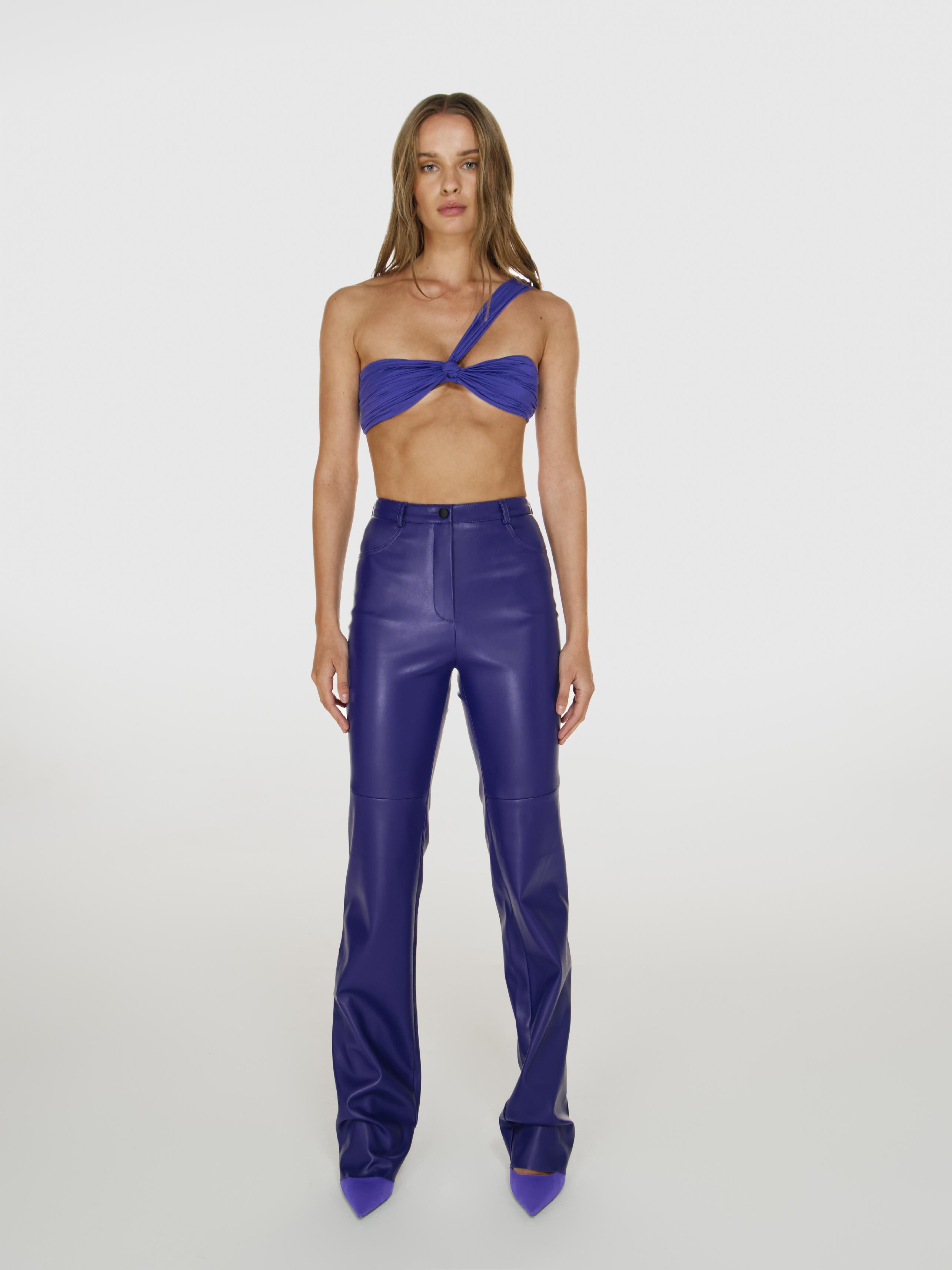 Full shot of a girl in a purple one shoulder crop top and purple vegan leather pants with straight leg